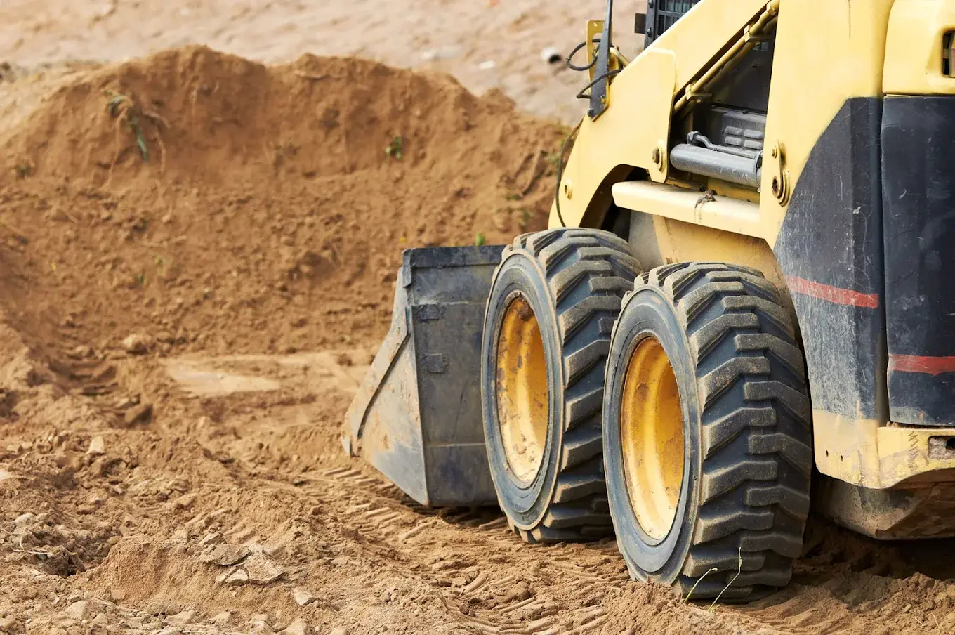 Professional Bobcat skid steer excavator in action - heavy-duty equipment for site grading, excavation, and land preparation